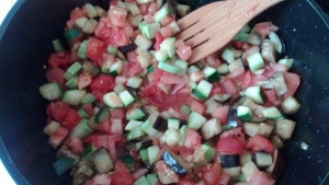 Далее нарезаем консервированные помидоры, чуть мельче, чем остальные овощи и вместе с соком добавляем в сковороду. 