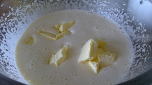 Добавляем молоко, размягченное сливочное масло. 1 столовую ложку сливочного масла оставляем для карамели.